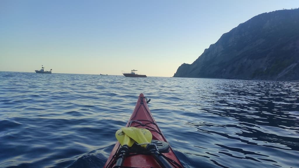 Kayak lungo una costa rocciosa, acqua calma.